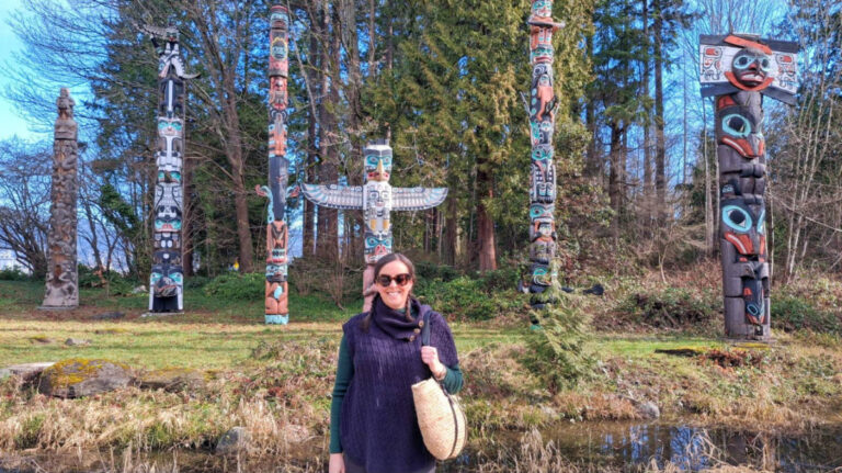 Author Catherine standing in front of the totem poles at Stanley Park