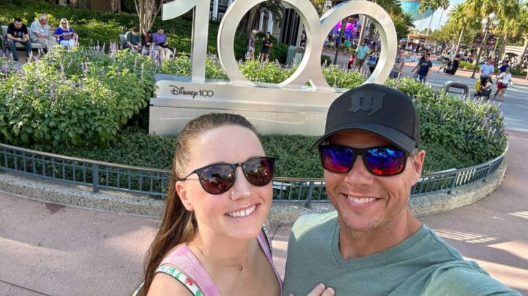 Author Katie with her husband taking a selfie near the Disney 100 mural