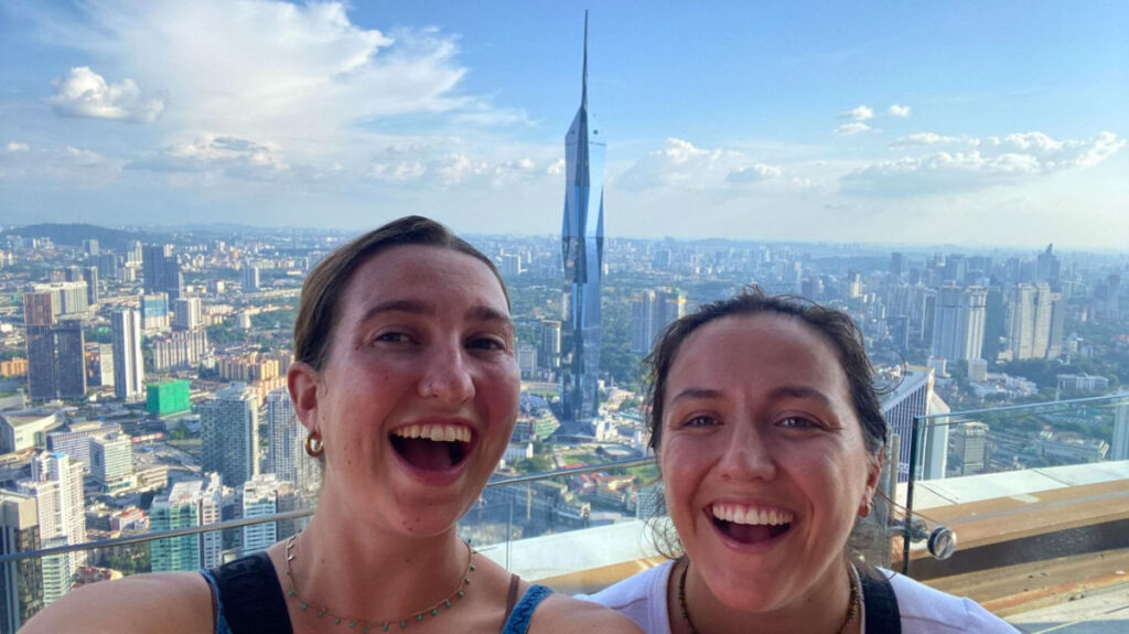 Author Laura and her partner standing atop Malaysia’s Sky Tower with the Merdeka 118 in the background