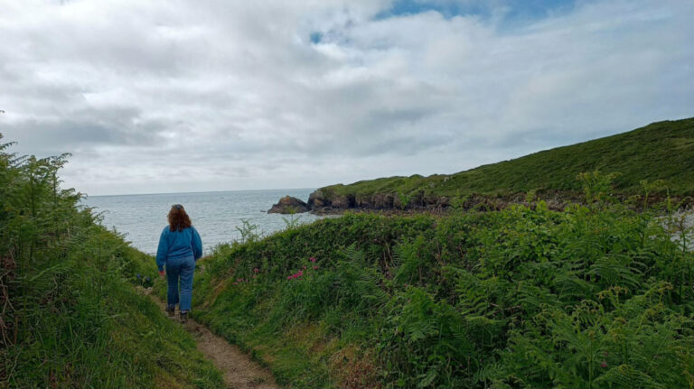 Author Ruthie walks on a path by the ocean in Pembrokeshire