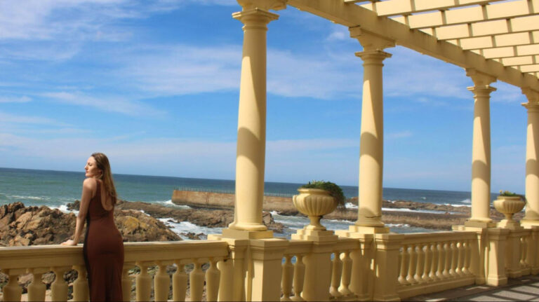 Author Sky in a dress stands under the yellow columns of Pergola da Foz in Porto
