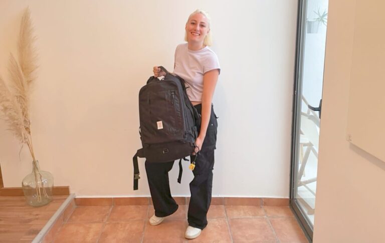 The author Sky Ariella carrying her Travel Bag against a white wall