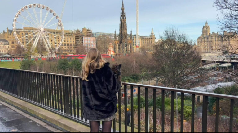 Author Sky holding her pet dog while looking at the Ferris wheel in Edinburgh