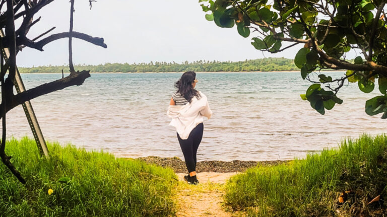 Author Vanessa stands at the edge of a narrow sandy path of the coast in Fajardo