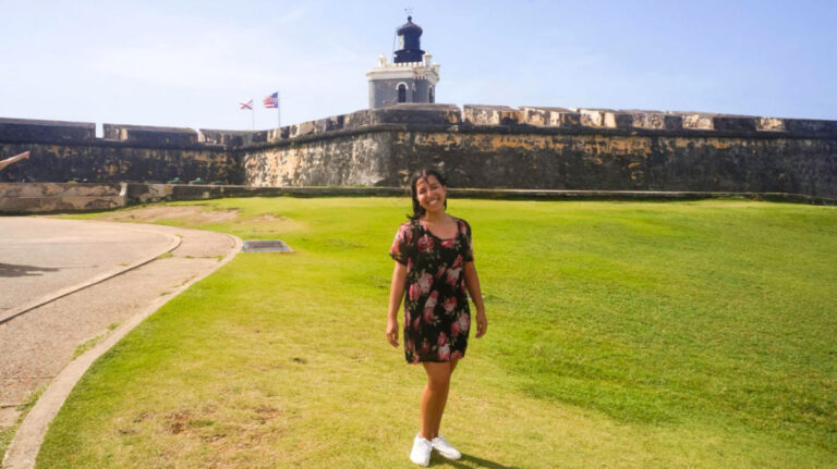 Author Vanessa posing for a photo on the grass field at Castillo San Felipe del Morro