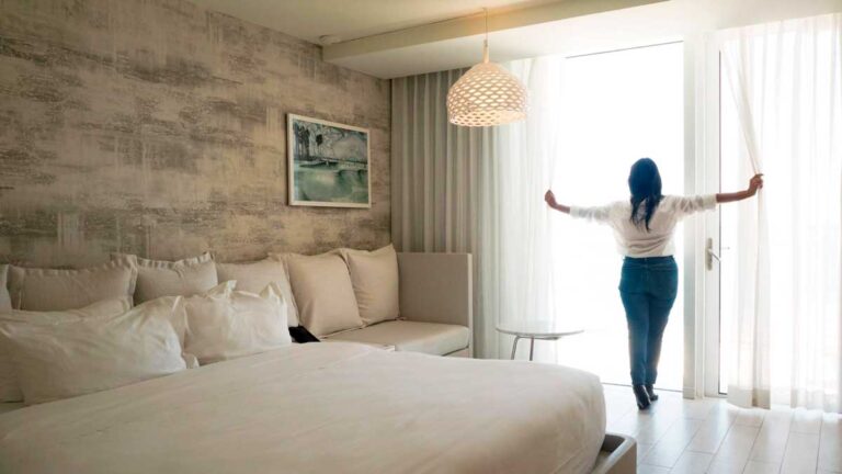 View of the author Vanessa Ramos holding curtains and admiring the view inside Condado Ocean Club