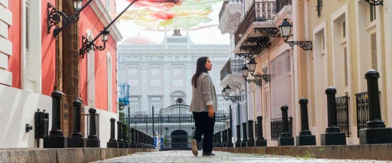 Author Vanessa strolls down a narrow street, surrounded by colorful buildings