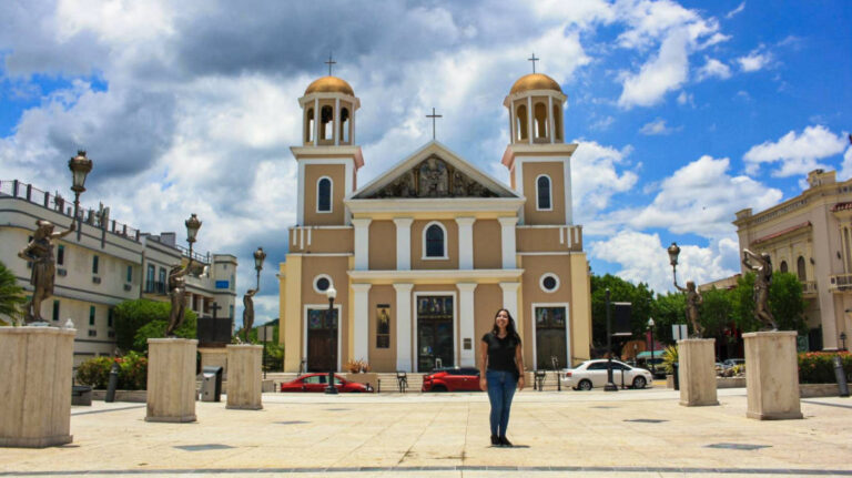 The author Vanessa Ramos, posing for a photo in front of the church in Plaza Cristóbal Colón