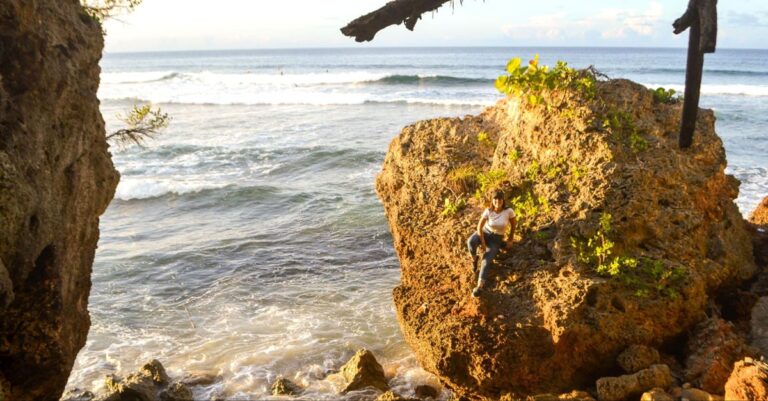 The author Vanessa sitting on a big boulder in Survival Beach