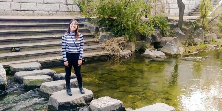 The author Vanessa Ramos standing on a rock in Cheonggyecheon River in Seoul