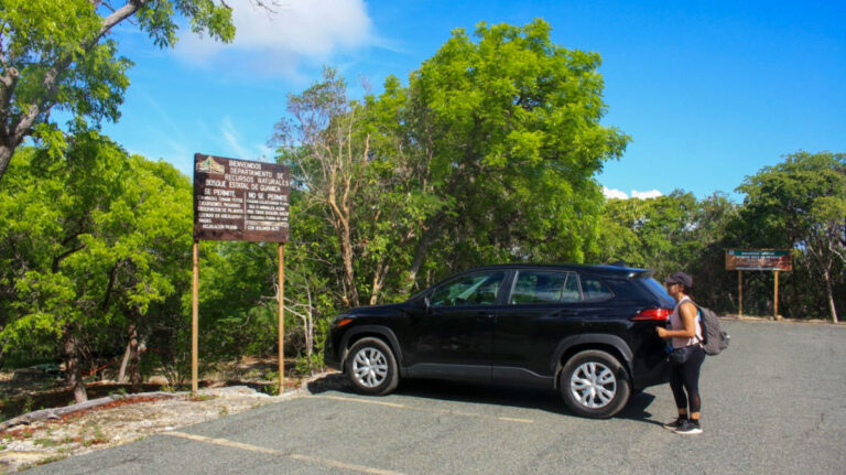 Author Vanessa standing next to the black rented car in Puerto Rico