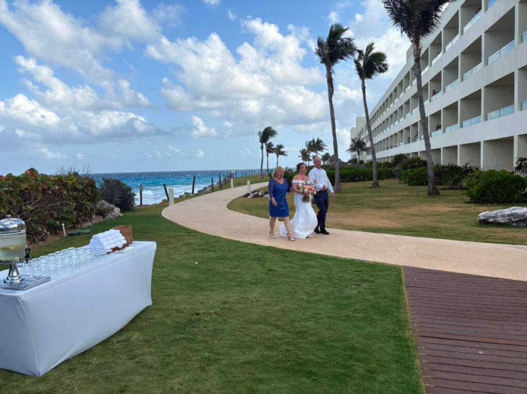 The bride and famil;y walking down the aisle of the beachside wedding reception