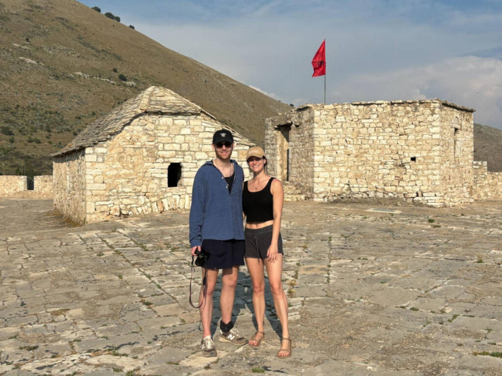 The author Betty Hurd and her boyfriend smiling for a photo at the top of Porto Palermo Castle