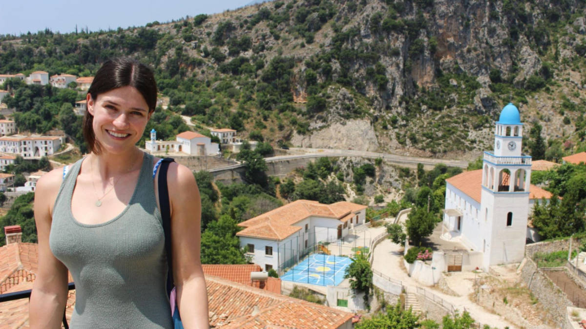 The author Betty Hurd smiling for a photo with an overlooking view in Albania