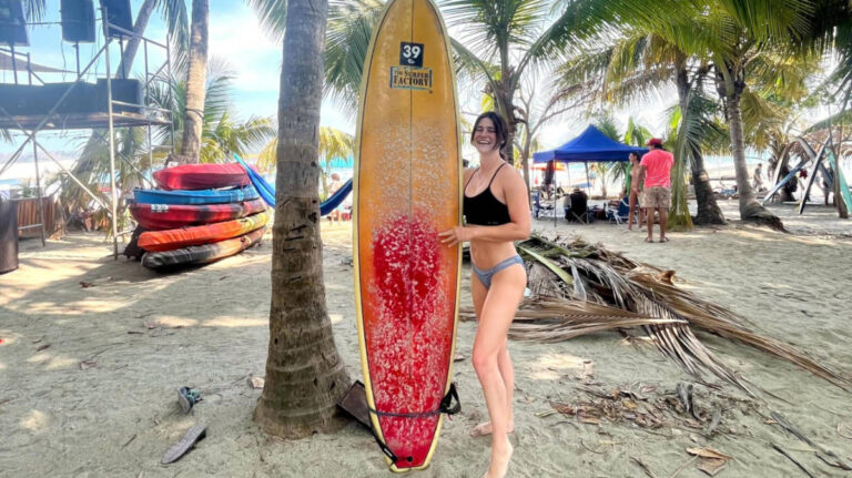 The author Betty Hurd holding a surfboard at the beach