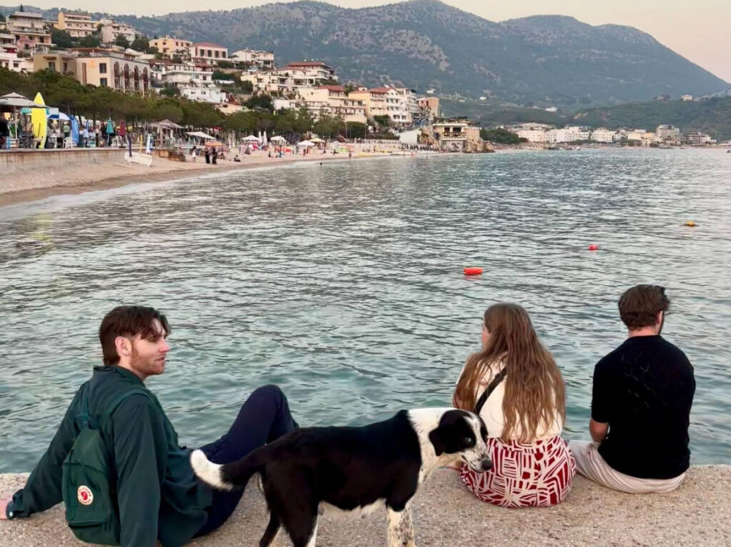 The author's friends relaxing with the stray dog at the boardwalk in Himarë