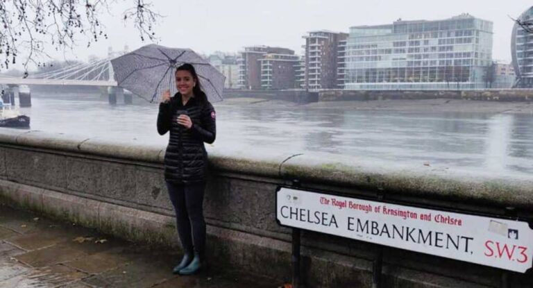 The author Brooke Horrobin standing in Chelsea Embankment while holding an umbrella during a rainy morning