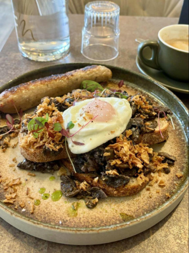 Closeup look of the plate with sausage, toast topped with egg at The Farmer’s Mistress