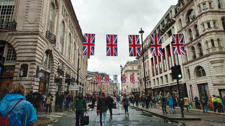 View of the crowd walking along the bustling city with UK flags hanging above