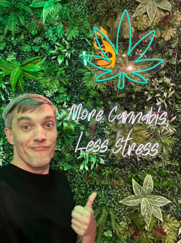 The author, Nate Hake smiling for a photo with a Cannabis sigange