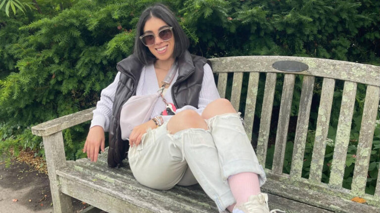 The author Claudicet Pena seated at a park bench in Boston