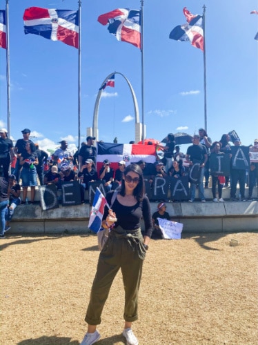 Claudicet Peña posing for a photo while holding a Dominican Republic flag in Plaza de la Bandera- Santo Domingo, Dominican Republic