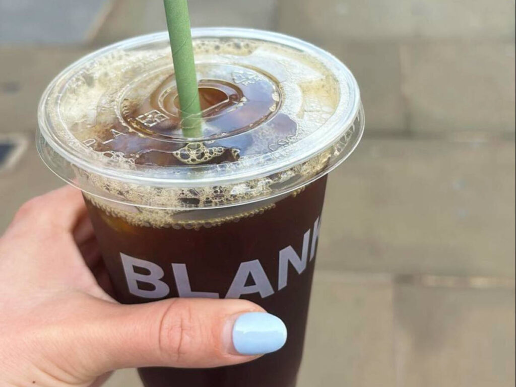 A hand holding a cup of cold brew from Blank Street