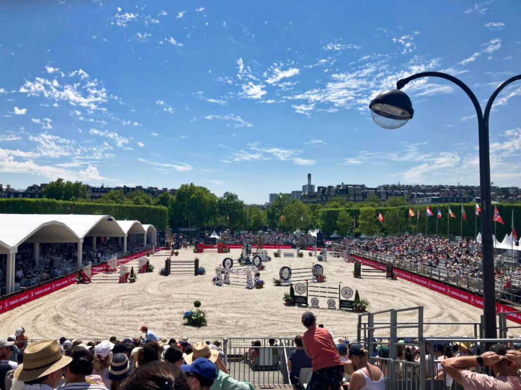 The crowd watching a horse show on a sunny day