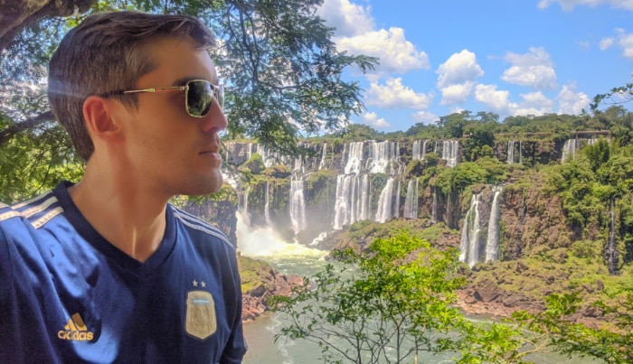 The author Nate Hake posing for a photo against the falls at Iguazu Falls