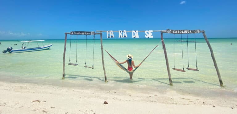 Clara sitting on a swing by the beach in Isla Holbox, Mexico