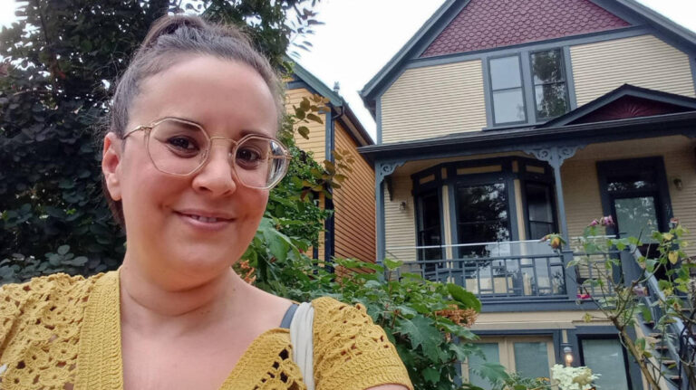 The author Catherine Driver smiling for a selfie with Jimi Hendrix’s grandmother's house on the background