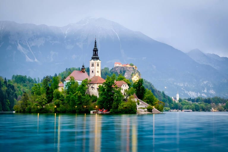 A lighthouse surrounded by greenery in Lake Bled Slovenia