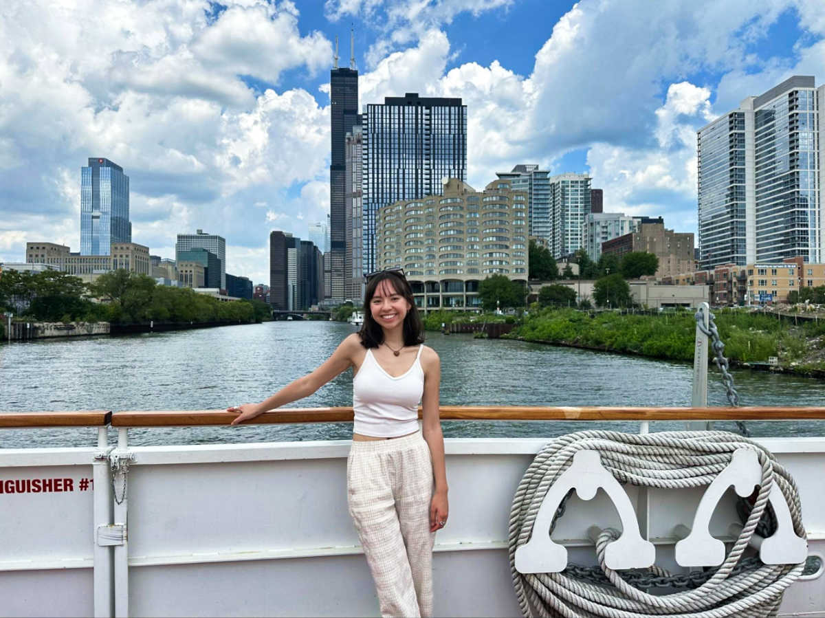 The author Lea Rose Allbaugh, posing for a photo on the Chicago river cruise with the tall buildings in the background