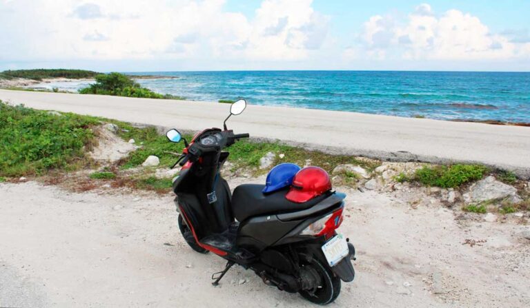 A motorcycle with a view of the blue water from a beach in Mexico
