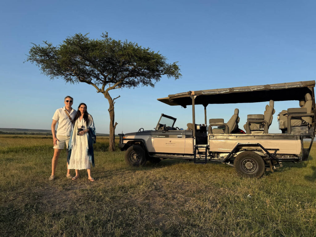 Travel Lemming founder Nate Hake and his partner Clara, posing for a photo beside the safari vehicle in Masai Mara