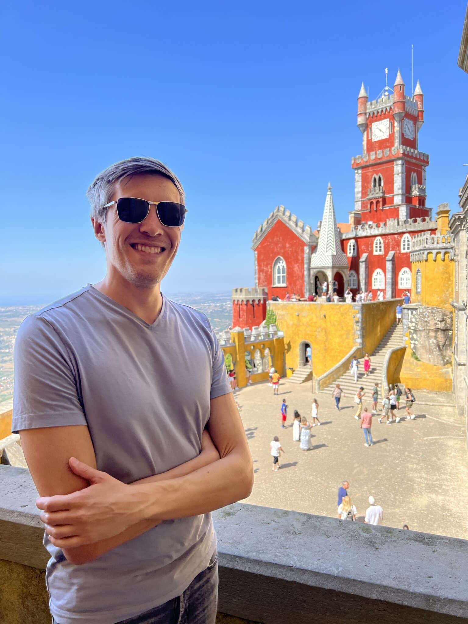 Nate Hake smiling for a photo with the Pena Palace on his background in Sintra, Portugal
