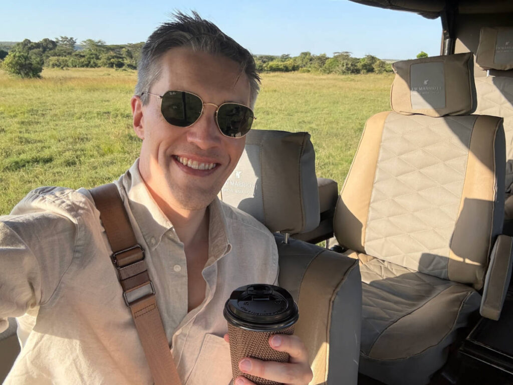 Travel Lemming founder Nate Hake, holding a cup of coffee while sitting comfortably on the vehicle
