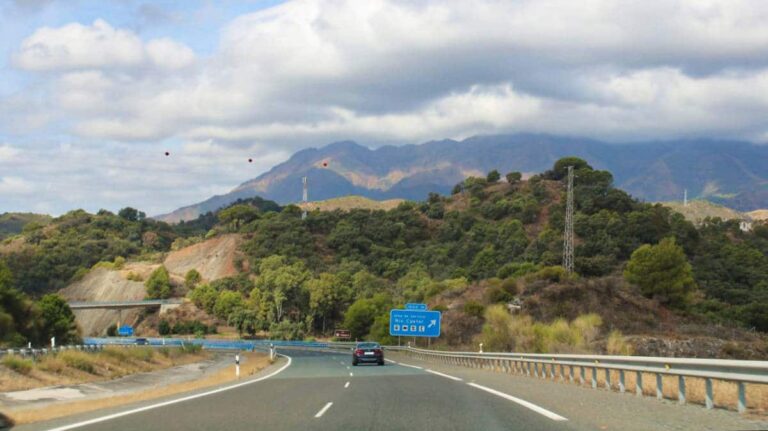 A highway stretches ahead, framed by mountains rising in the background