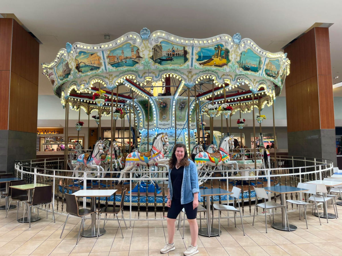 Author Elizabeth Demolat posing in front of a carousel at the Opry Mills Mall in Music Valley