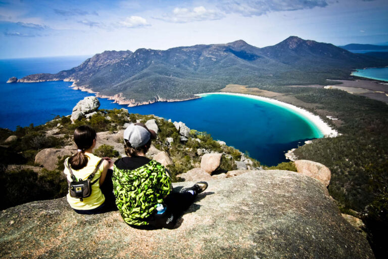 Two people admiring Wineglass bay from the top of the mountain