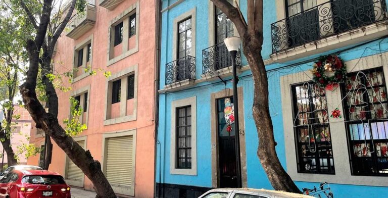 A vibrant pink and blue building with a car parked in front
