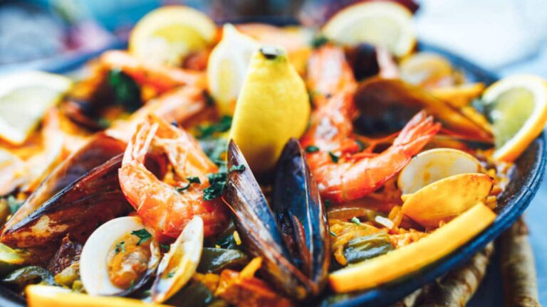 Closeup view of the paella topped with seafood and sliced lemons