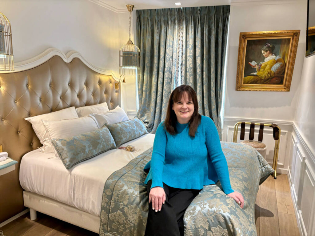 The author Rachel Kapelke-Dale sitting on her bed at the Académie Hôtel Saint Germain