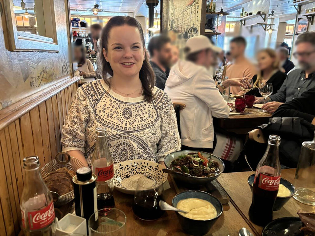 The author Rachel Kapelke-Dale, sitting at the crowded restaurant of Chez L’Ami Jean