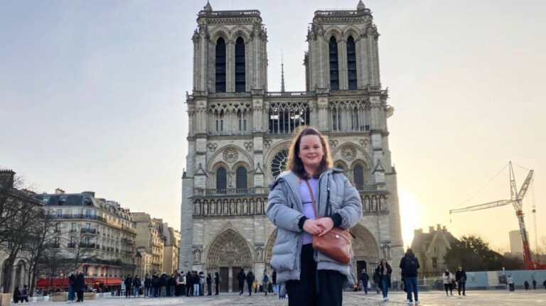 The author Rachel Kapelke-Dale standing in front of Notre Dame Cathedral