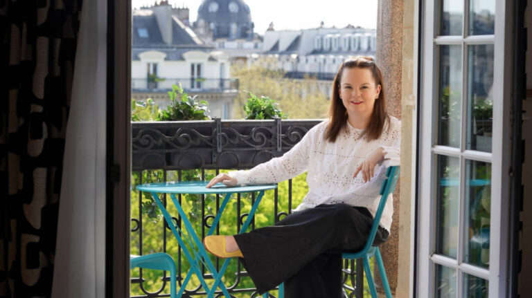 The author Rachel Kapelke-Dale sitting on a balcony of a hotel