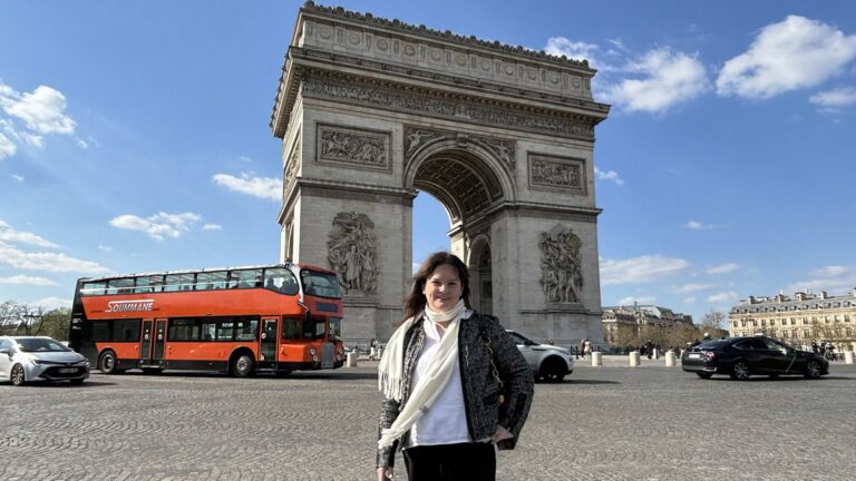 The author Rachel Kapelke-Dale posing for a photo in front of the Arc de Triomphe