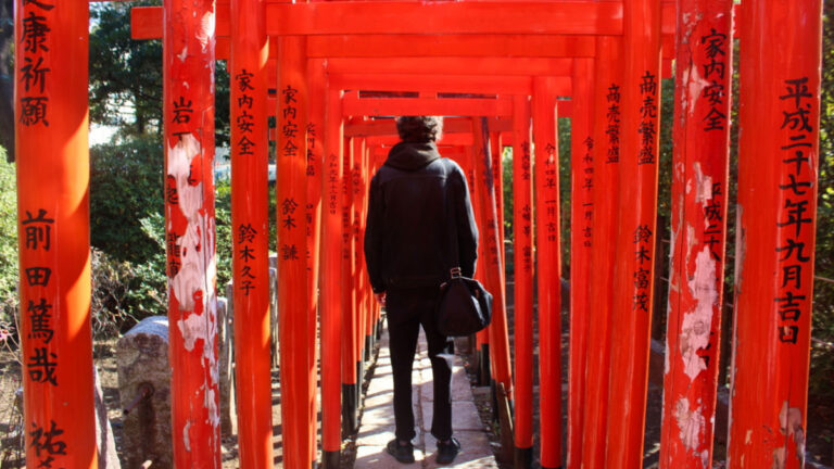 A man wearing black standing at the Red Torii gates at Nezu Shrine