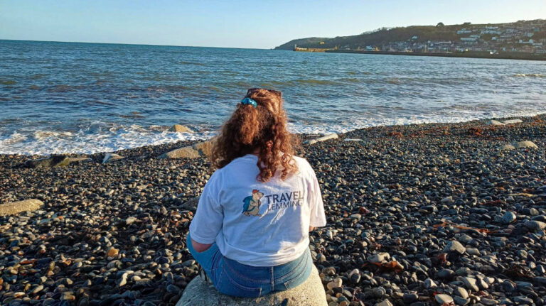 The author Ruthie sitting on a rock at the beach looking across to Newlyn