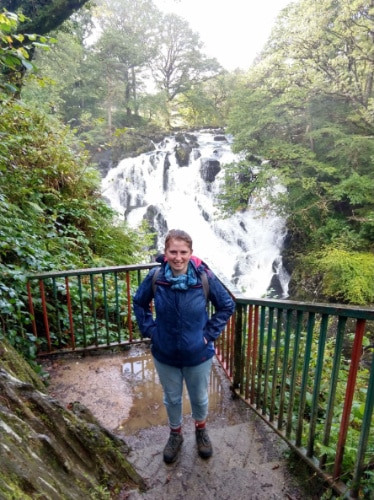 Ruthie Walters smiling for a photo with the Swallow Falls on her background in Wales